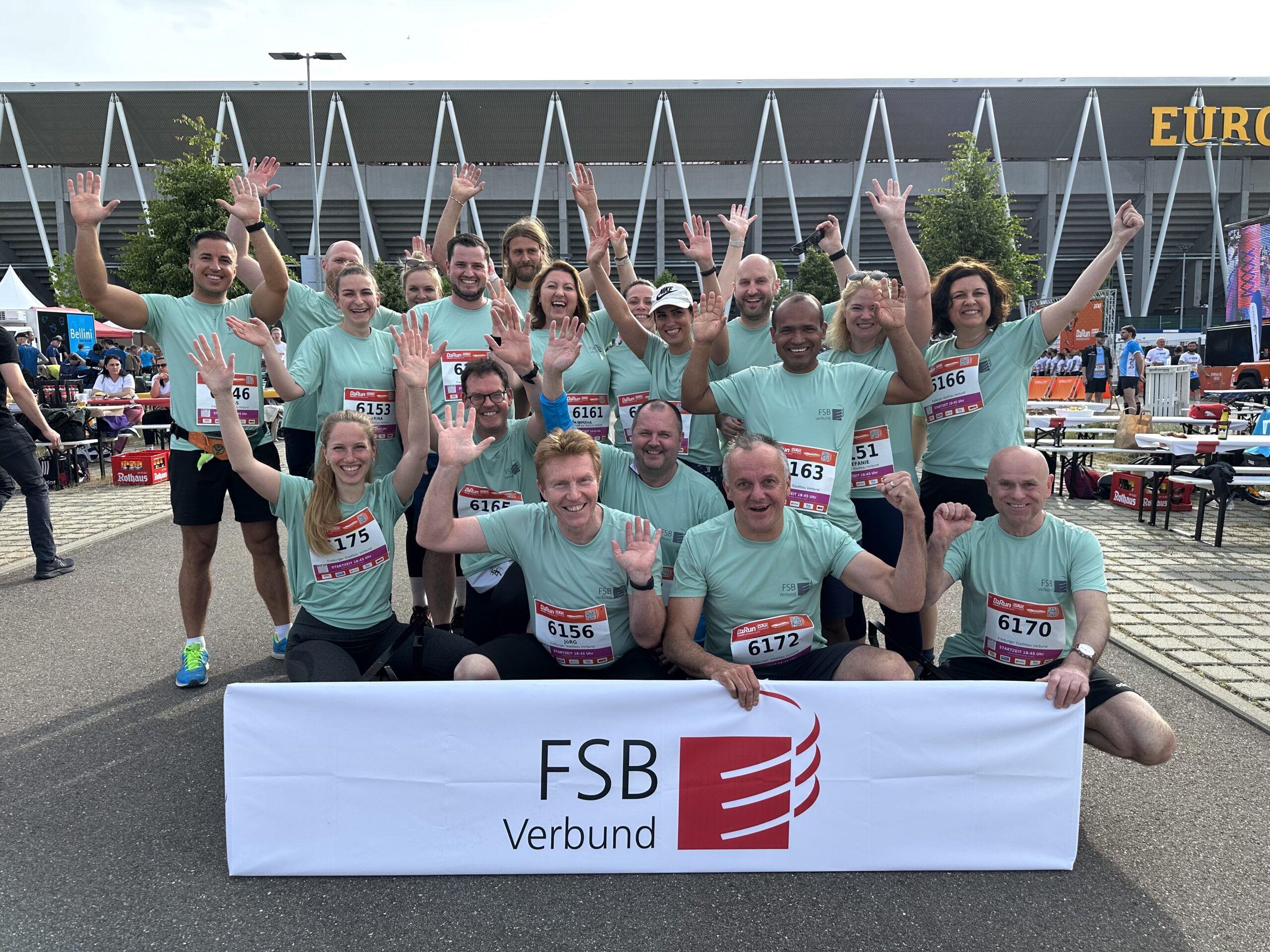 Ein Gruppenbild, mit mehreren Personen drauf, die als Team auftreten mit einheitlichen T-Shirts